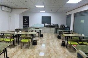 Une salle de classe avec des tables et des chaises, un tableau noir et une fenêtre.