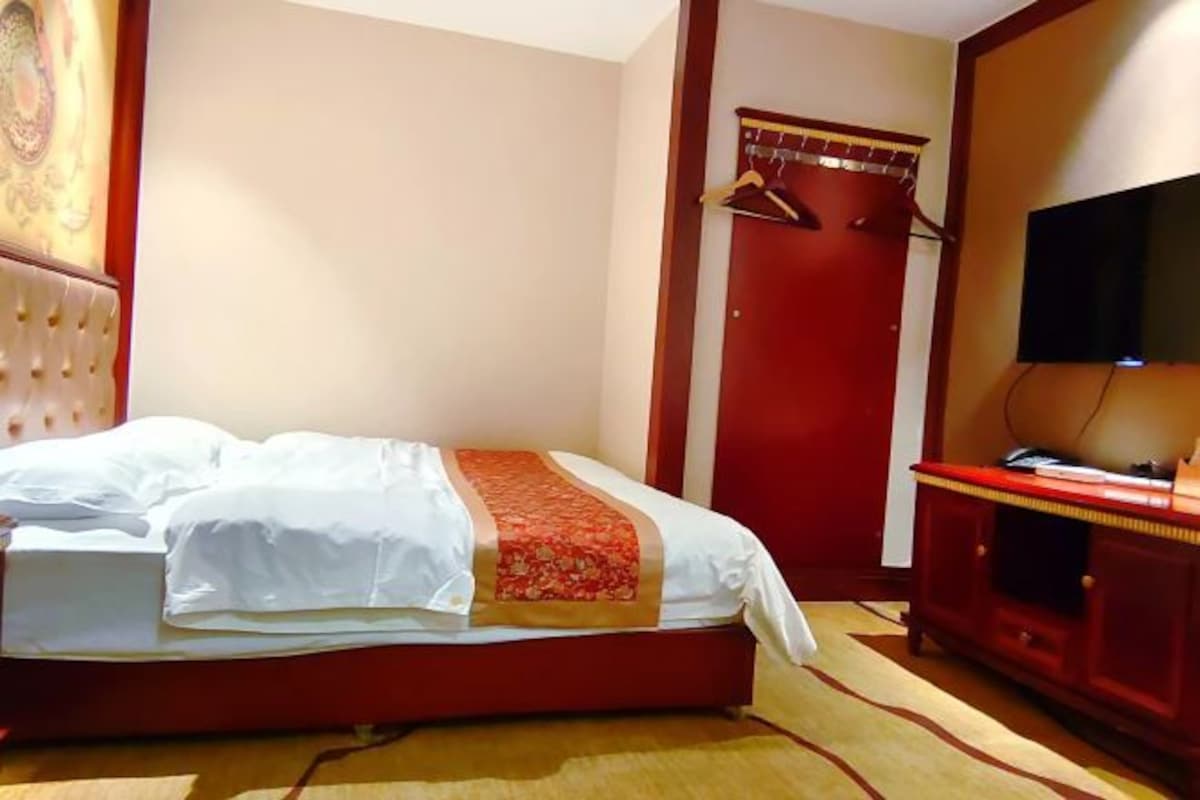 A hotel room with a bed, a TV, a wardrobe, and a door.