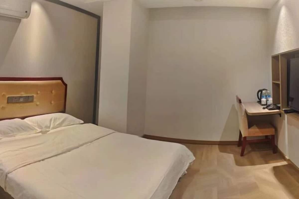 A hotel room with a bed, a desk, and a chair.