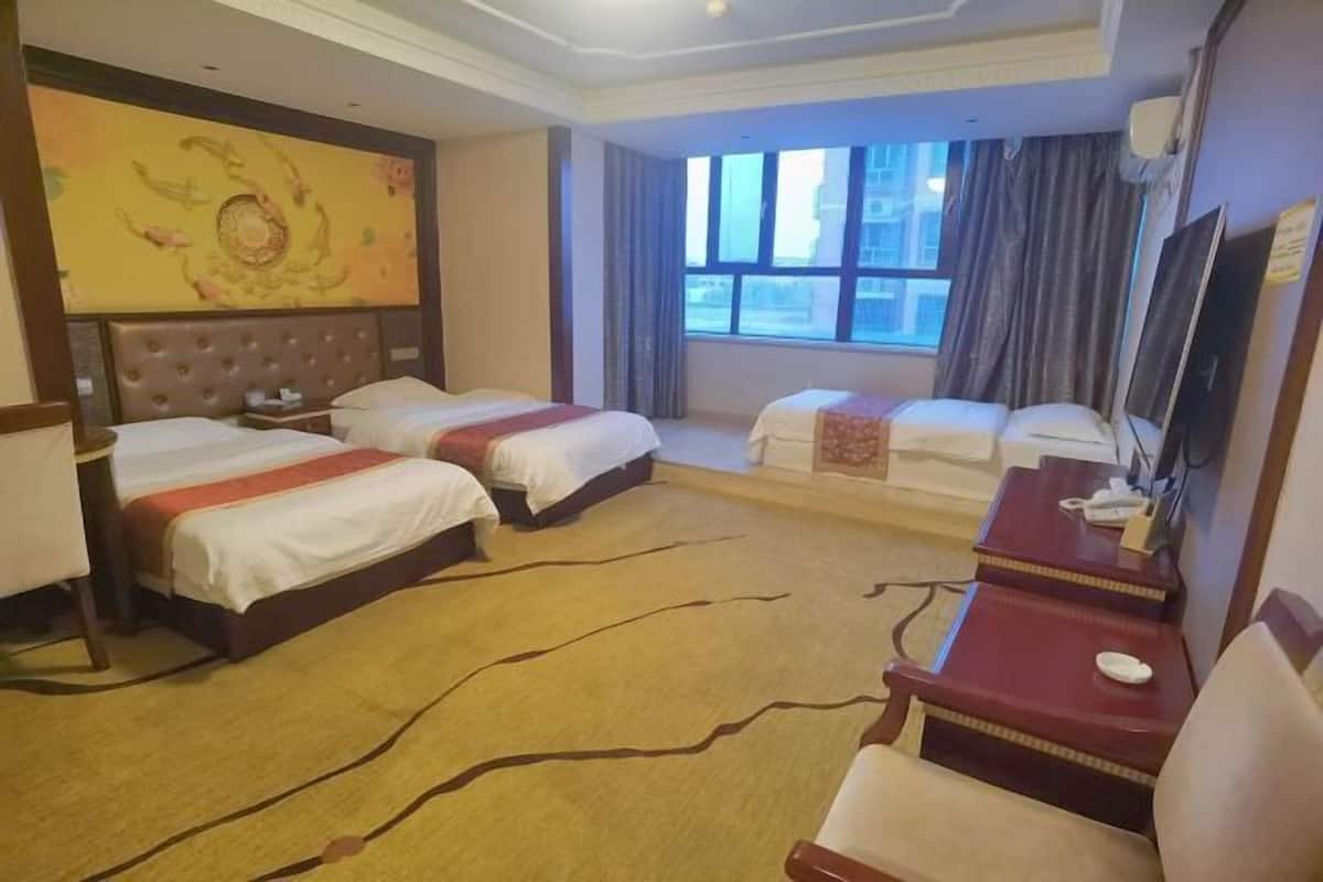 A hotel room with two beds, a desk, a chair, a TV, and a large window.