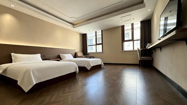 A hotel room with two beds, a large mirror, and a TV. - Klamar Law Rode Hotel (Karamay)