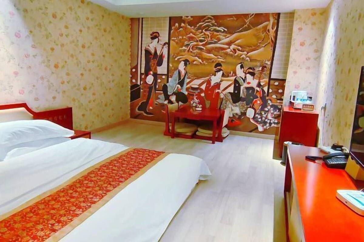 A hotel room with two beds, a desk, a chair, and a large wall mural.