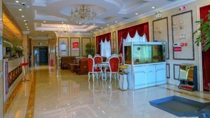 A hotel lobby with a reception desk, seating area, and a fish tank. - Klamar Law Rode Hotel (Karamay)