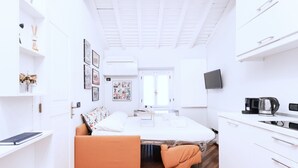 A compact room with a bed, a small kitchenette, a TV, and a window. - Easylife - Delicious Studio in Brera/Duomo (Milano)