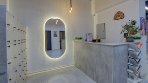 A reception area with a modern design, including a reception desk, a large mirror, and a wall-mounted plant. - Hostel Pro (Bishkek)