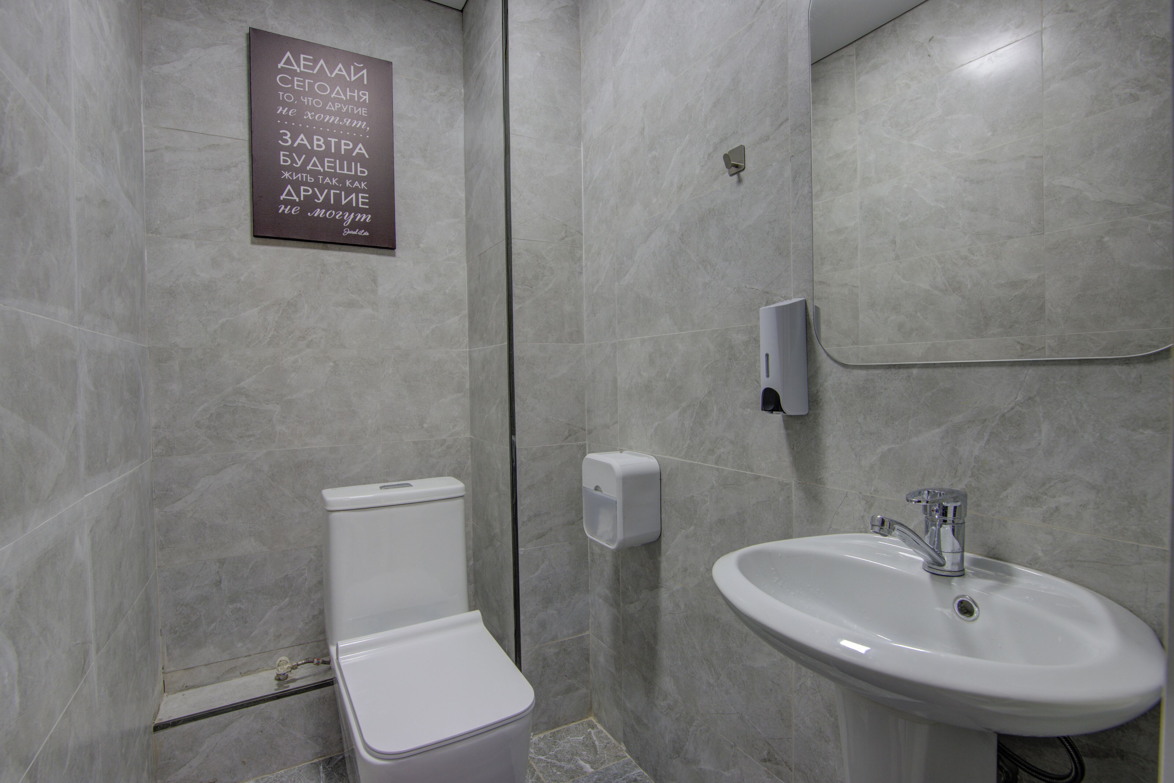 A modern bathroom with a toilet, sink, and a sign on the wall.
