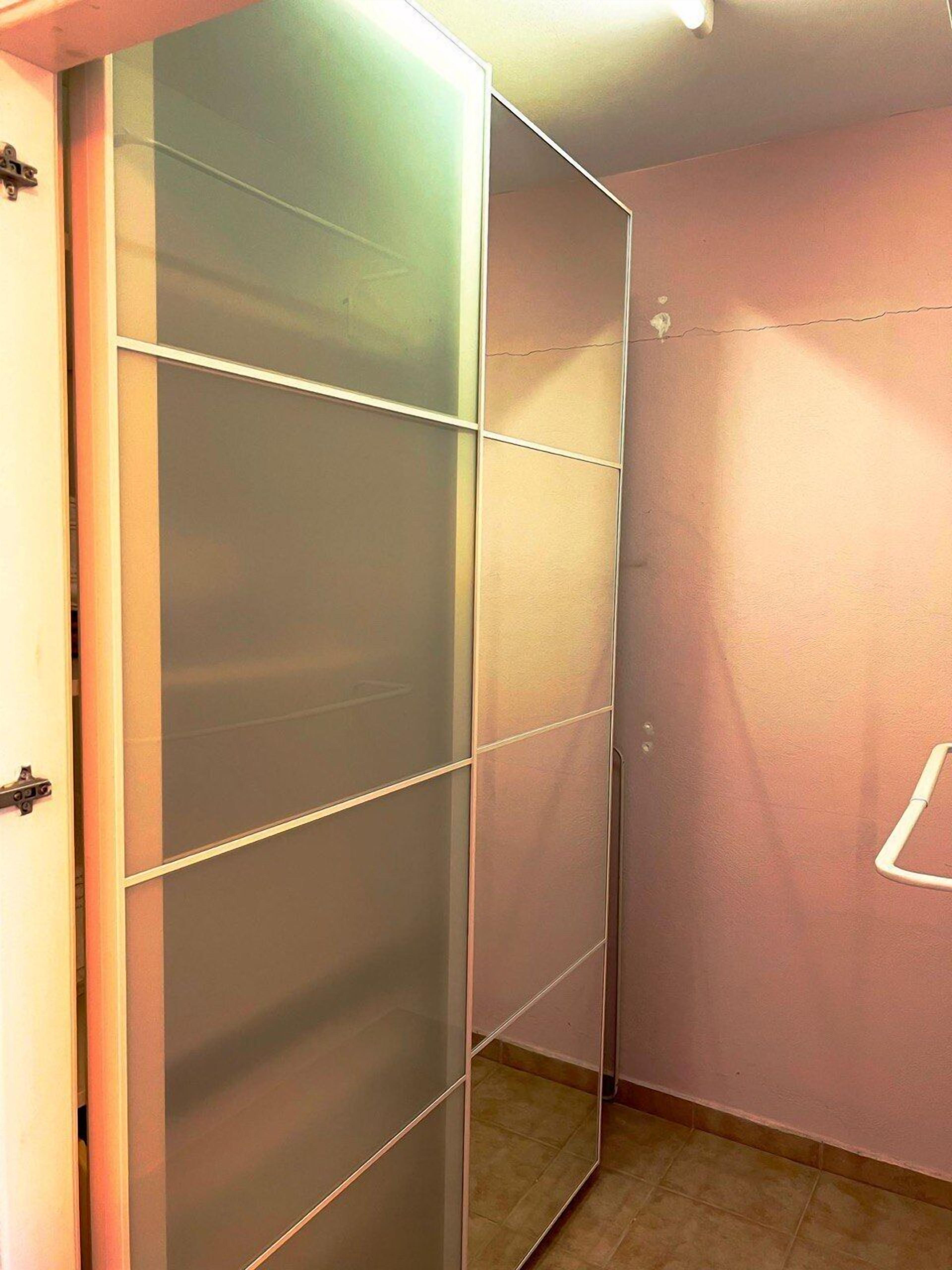 A room with a sliding door, a light switch on the wall, and a tiled floor.