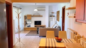 A modern kitchen with a dining area, a sofa, and a TV in the background. - SV Apartment with sea view (Corfu)