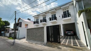 Une maison moderne à deux étages, dotée d’un garage, d’une allée et d’une voiture visible, garée à l’intérieur.
