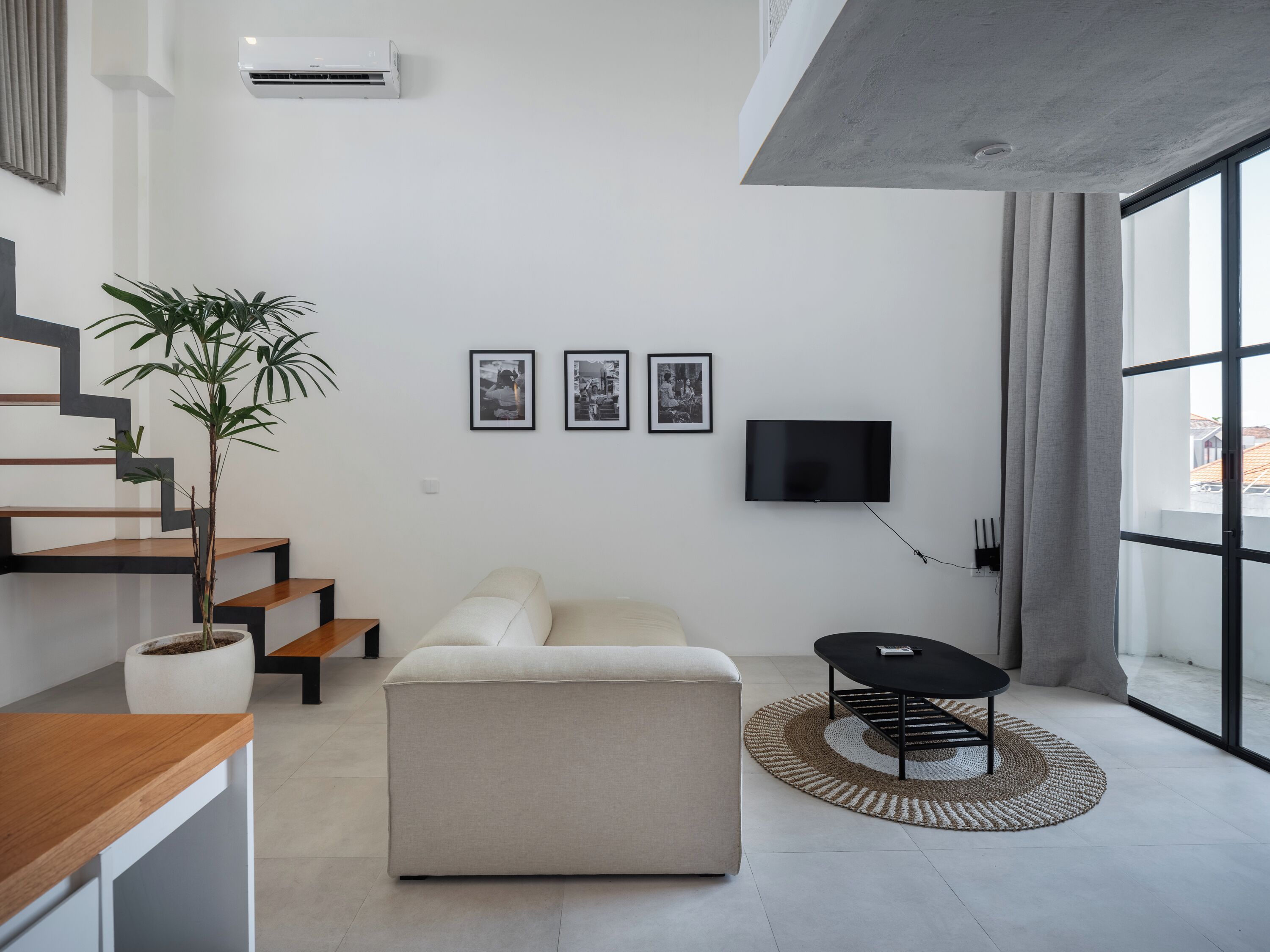 Un salon moderne avec un canapé, un téléviseur et un escalier.