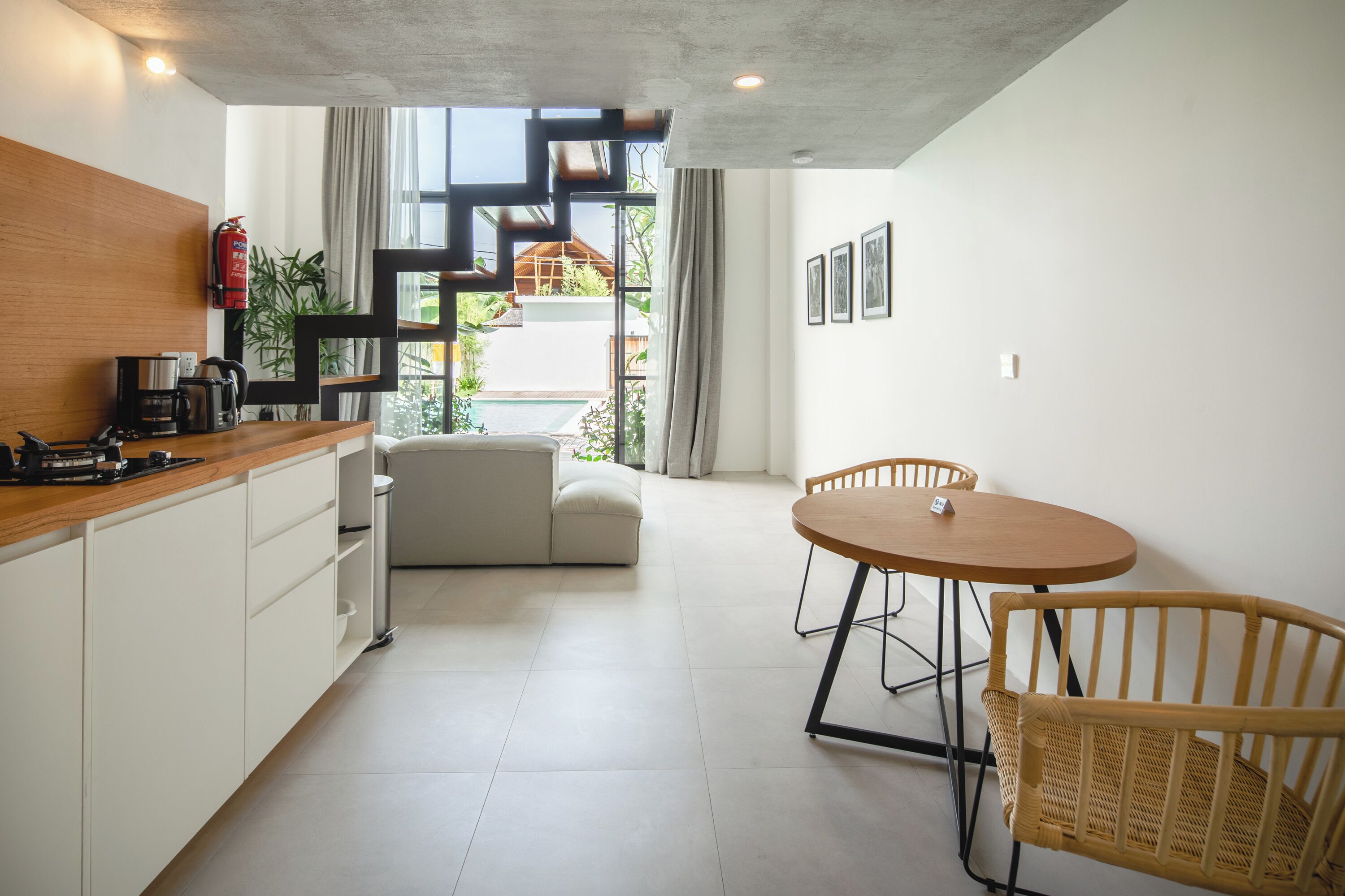 Eine moderne Küche mit weißen Schränken, einer Holz Arbeitsplatte und einem Essbereich mit rundem Tisch und Korbstühlen.