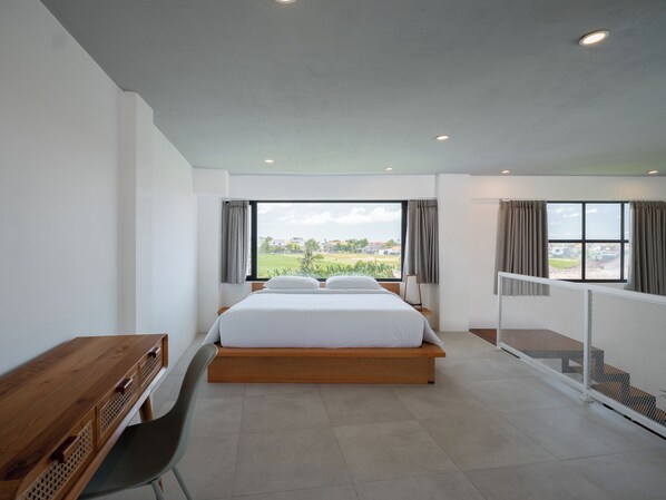 Un dormitorio moderno con una cama grande, un escritorio de madera y vistas al exterior.
