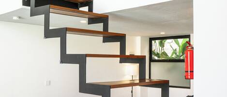 Un interior moderno con una escalera que conduce a un nivel superior, un comedor con mesa y sillas, y un sofá.