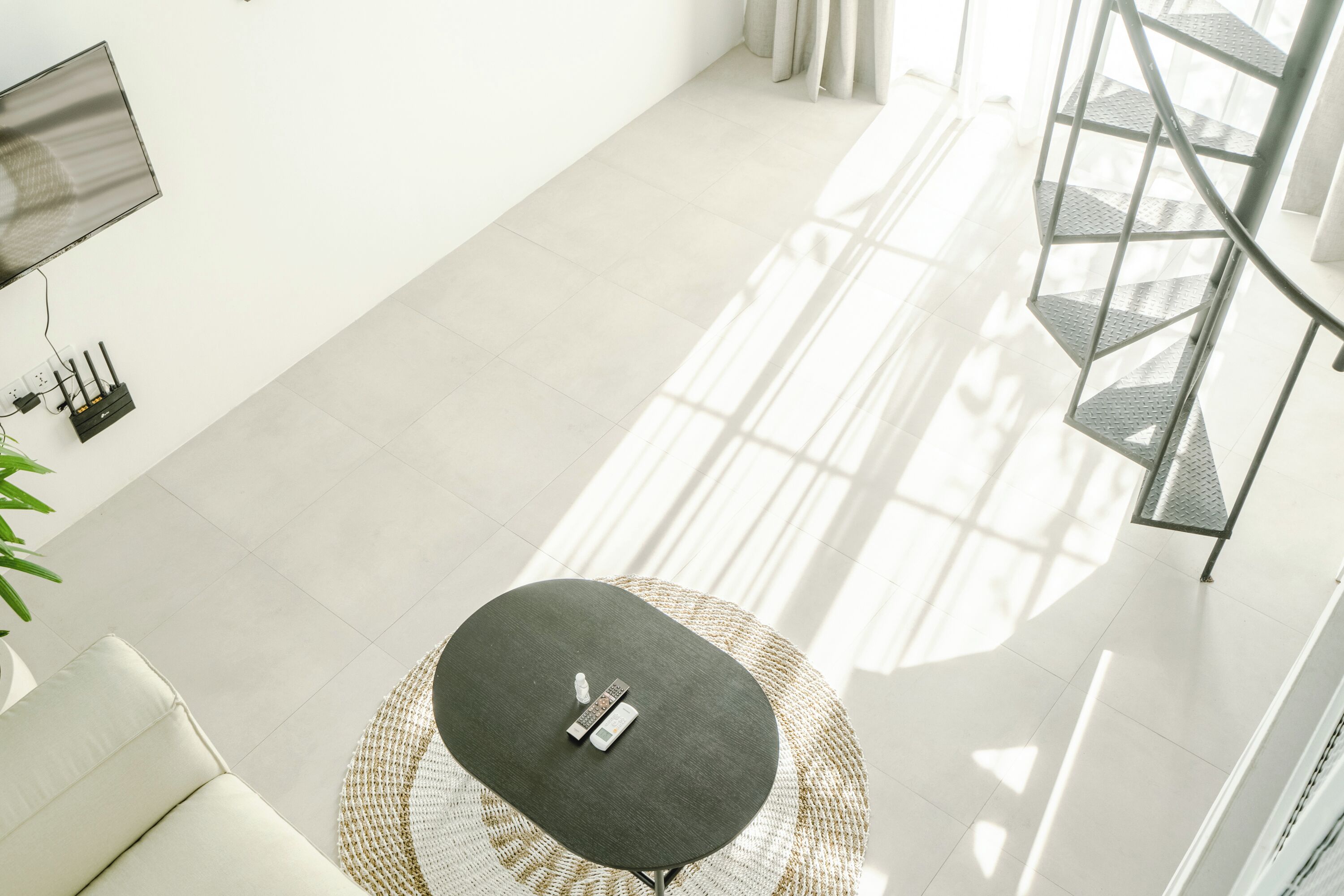 A modern living room with a round table, a sofa, a TV, and a staircase.