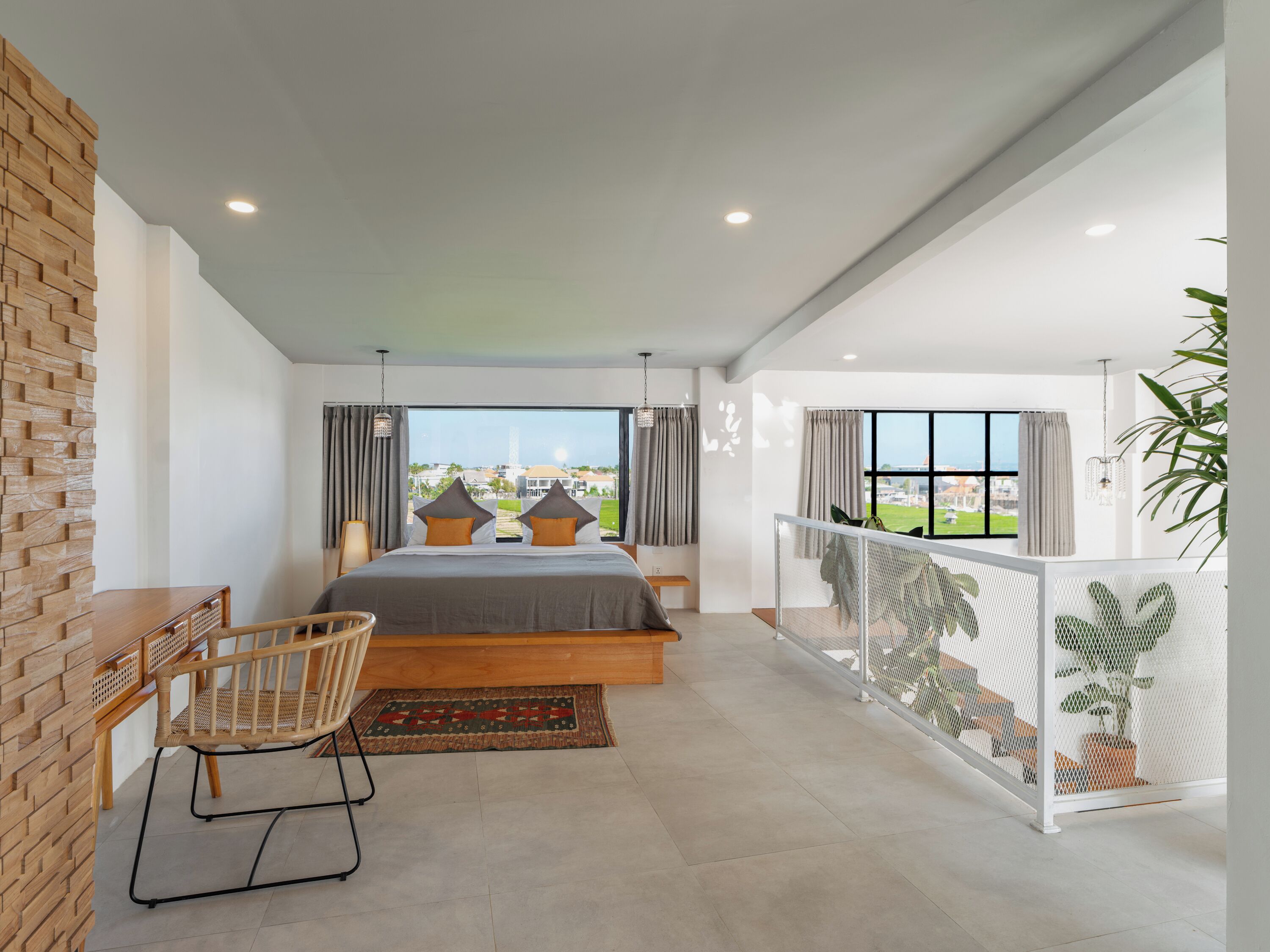 A modern bedroom with a large bed, a desk, and a view of the city.
