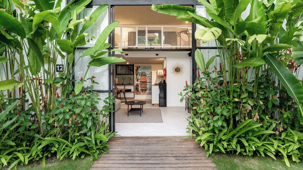 A modern two-story house with a wooden deck leading to a dining area and kitchen.