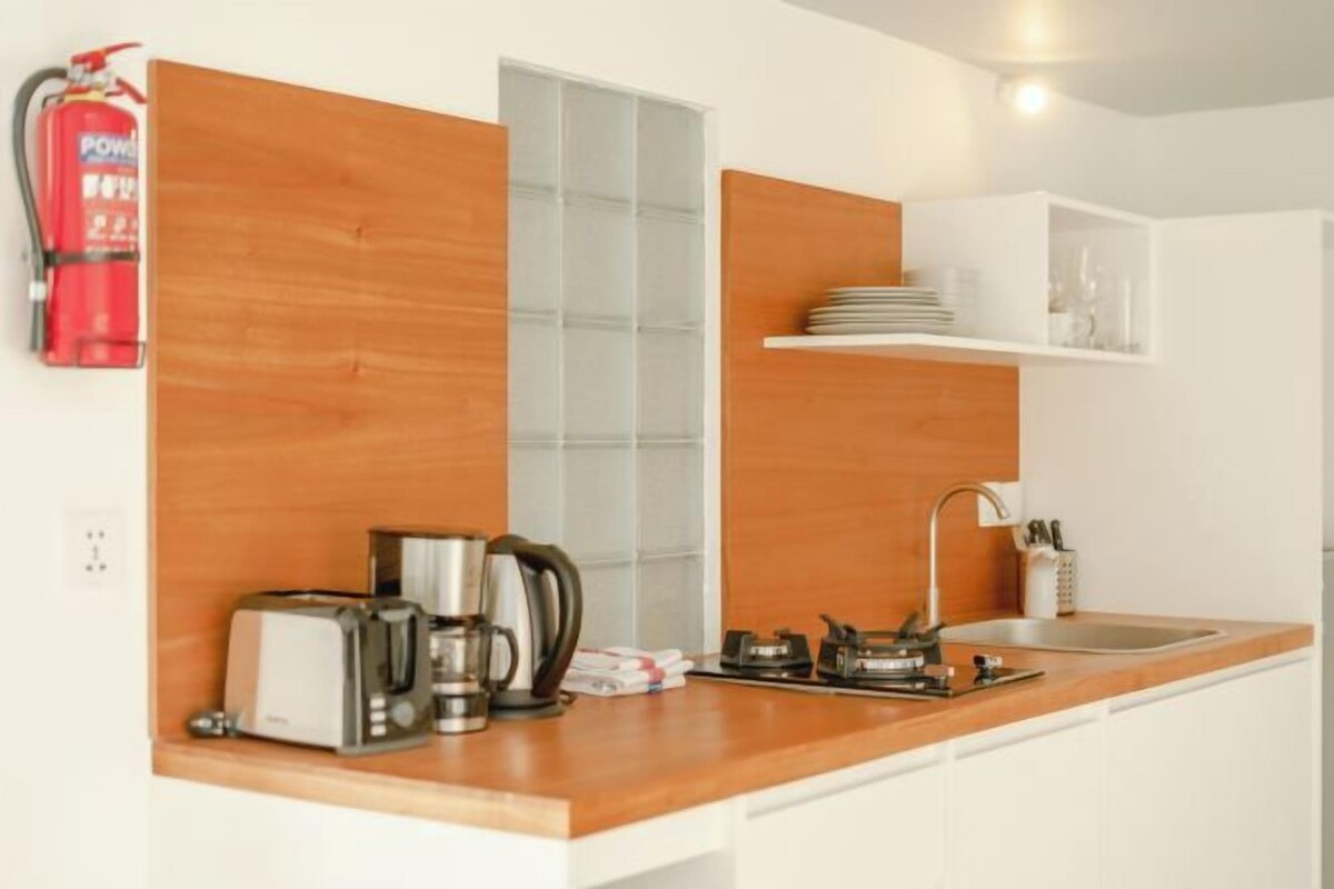 Una cocina moderna con encimera de madera, un tostador, un hervidor y un lavabo.