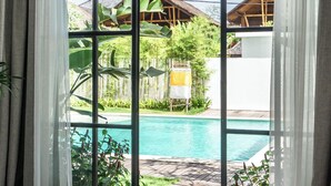 A room with a large window overlooking a swimming pool and a wooden deck.