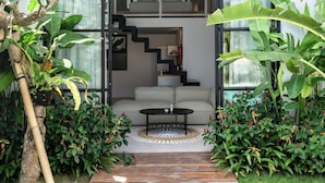 A modern house with a wooden deck leading to a white sofa and a staircase.