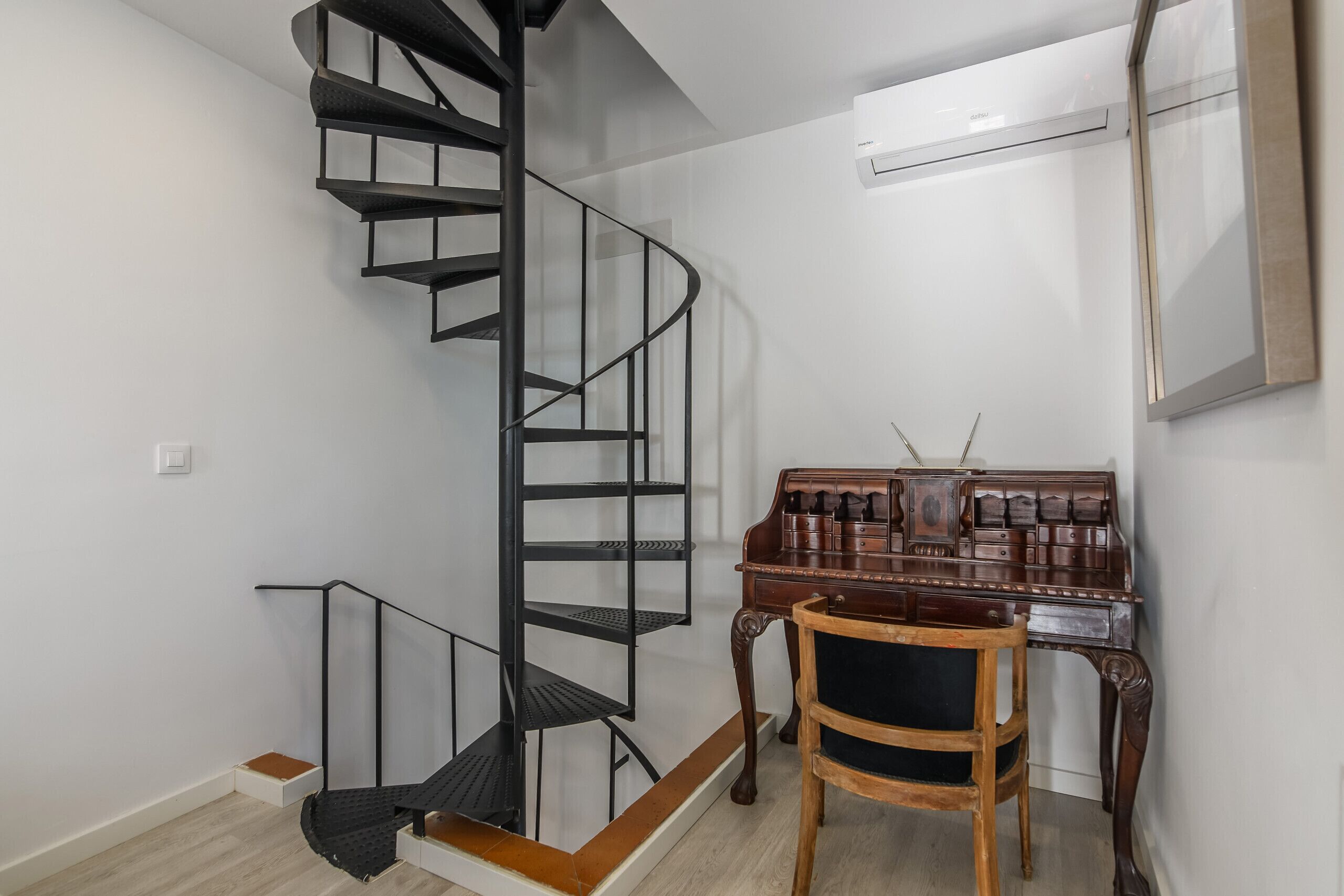 Een modern interieur met een wenteltrap, een houten bureau en een stoel.