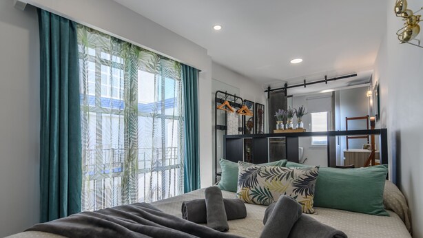 A modern hotel room with a large bed, a wardrobe with a mirror, and a view of the city through the window. - Estudio del Astillero - Ayamonte Centre AEHASP00 (Ayamonte)