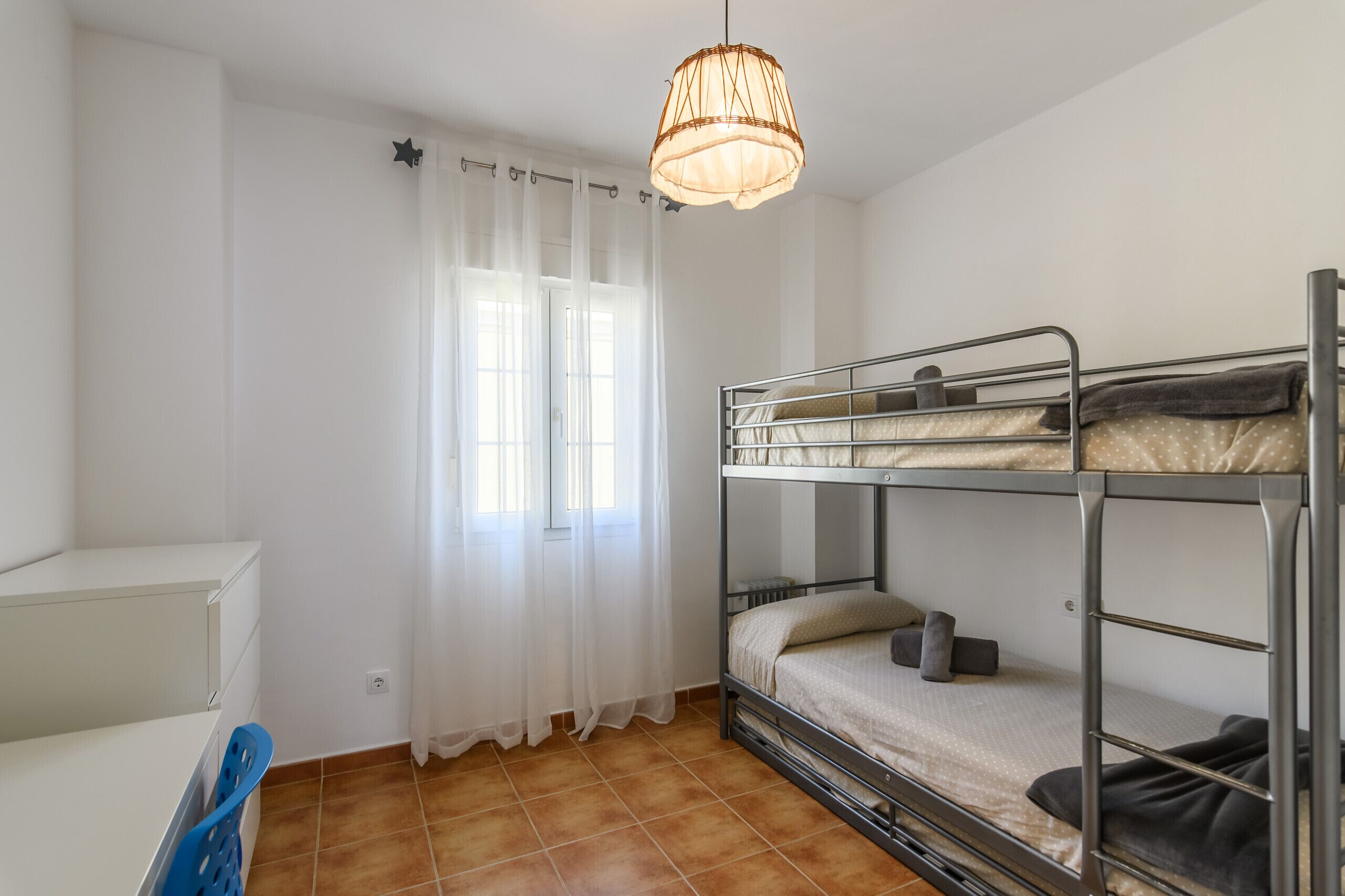 Une chambre de dortoir avec des lits superposés, un bureau et une chaise.