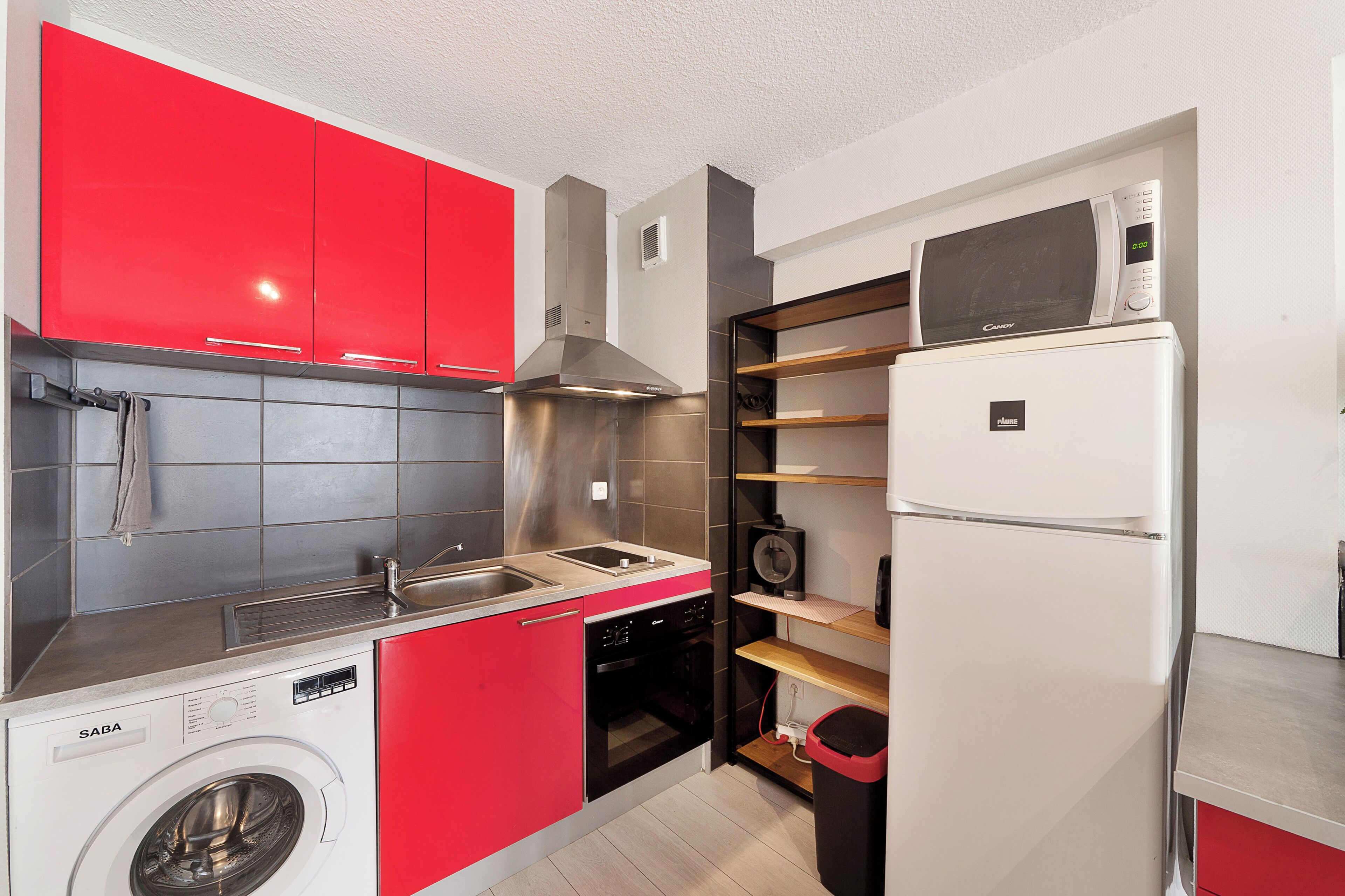 Una cocina compacta equipada con lavadora, microondas y refrigerador.
