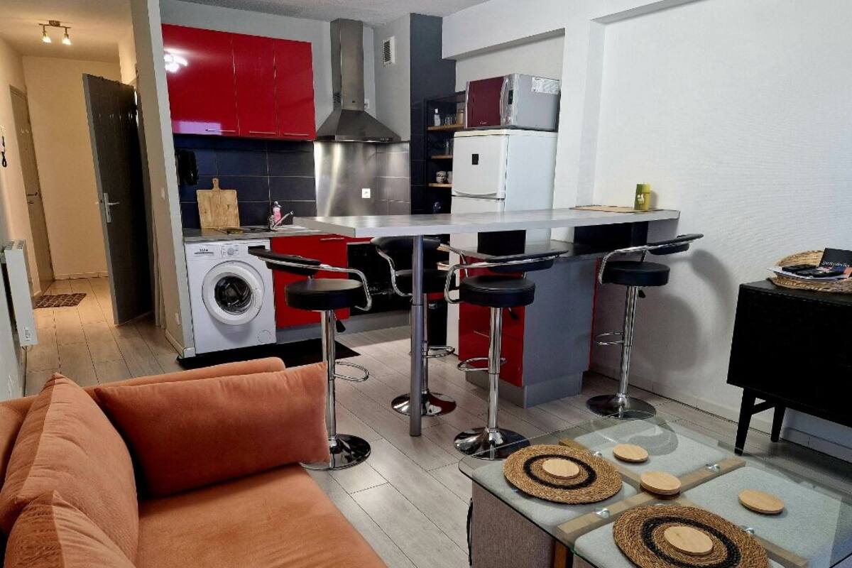 Un espacio habitable compacto con kitchenette, lavadora y sofá.