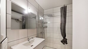 A modern bathroom with a white sink, mirror, and glass shower enclosure. - Le Petit Coin de Lavaur (Lavaur)
