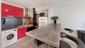A compact kitchen with red cabinets, a built-in washing machine, and a modern bar area. - Le Petit Coin de Lavaur (Lavaur)