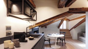A modern kitchen with a central island, built-in appliances, and a dining area with a round table and chairs. - Palazzina Riva (Venice)