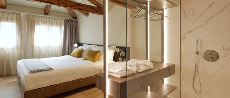 Ein modernes Schlafzimmer mit Holzboden, einem großen Bett, einer Glasabtrennung, einem Badezimmer mit Dusche und Marmorwänden.