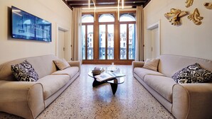 A spacious living room with two sofas, a coffee table, and a large TV screen displaying a cityscape. - Palazzina Riva (Venice)