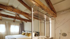 A modern bedroom with a wooden ceiling, a large bed, a glass partition, and a separate shower area. - Palazzina Riva (Venice)