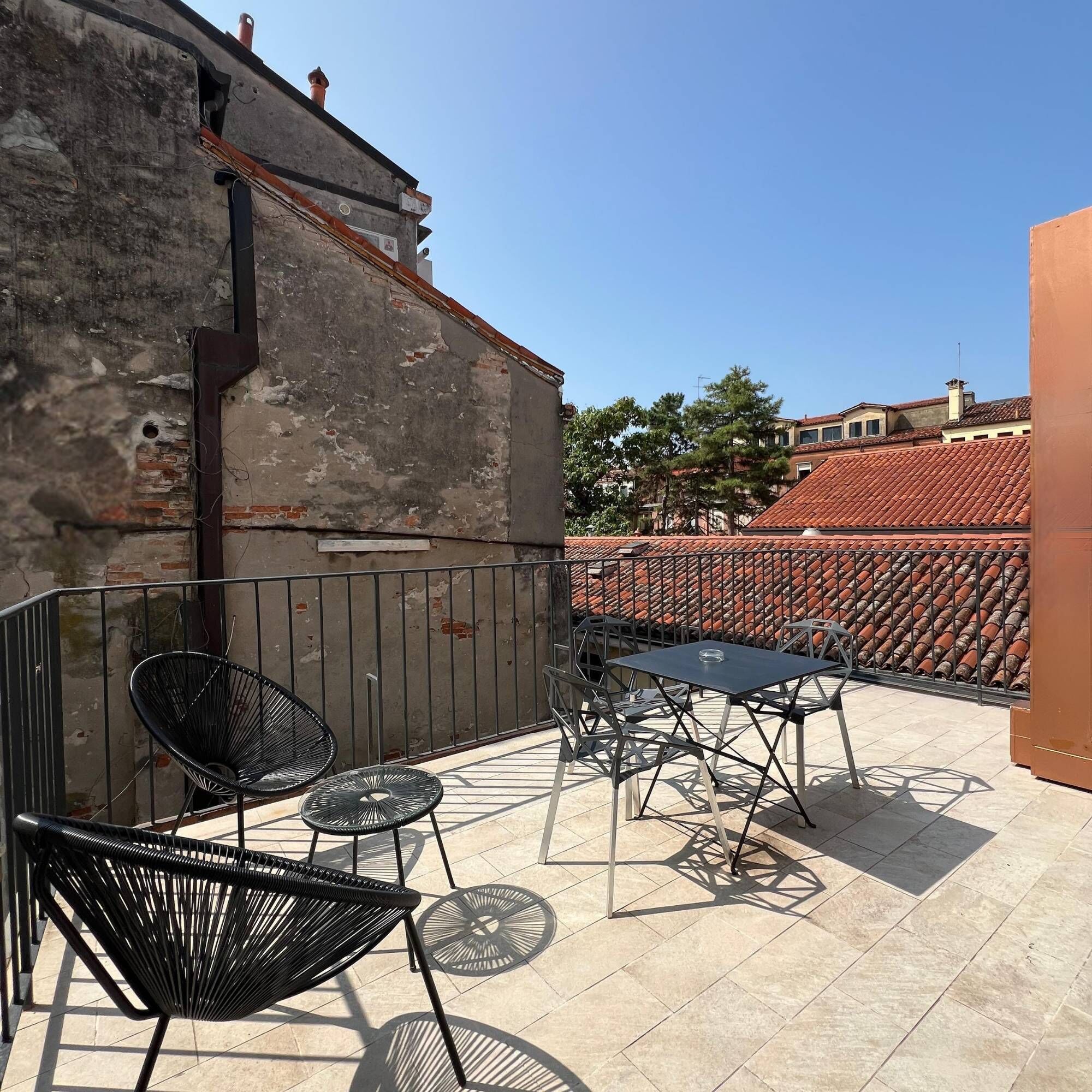 Une terrasse sur le toit, aménagée avec des espaces extérieurs comprenant des chaises et une table, et offrant une vue sur le paysage urbain.