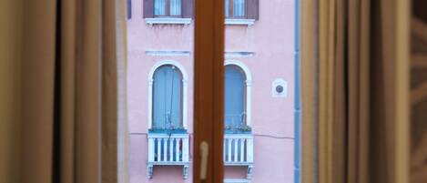 Una habitación con ventana que da a un edificio con balcones.