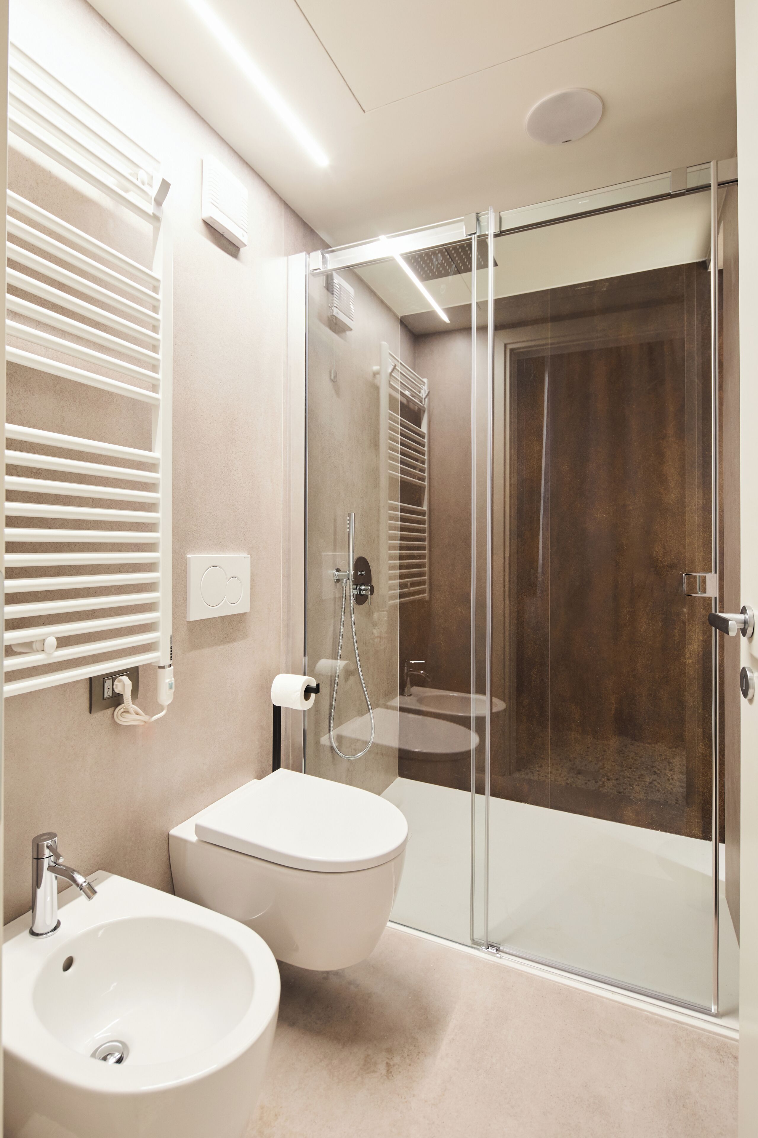 Un baño moderno con ducha de vidrio, lavamanos blanco y retrete.