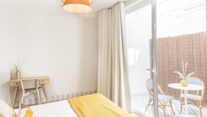 Ein Hotelzimmer mit Bett, Schreibtisch und Stuhl. Ein Balkon mit Tisch und Stühlen ist vorhanden.