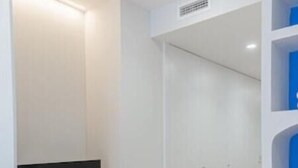 Ein modernes Zimmer mit Flachbildfernseher auf einer Holzkammer, einem Kleiderschrank und Weidenkörben auf dem Boden.