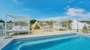 Una piscina con sillas de descanso y una zona de estar cubierta.