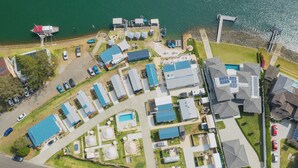 Vista aérea de una zona residencial con casas, una piscina y un muelle junto al agua.