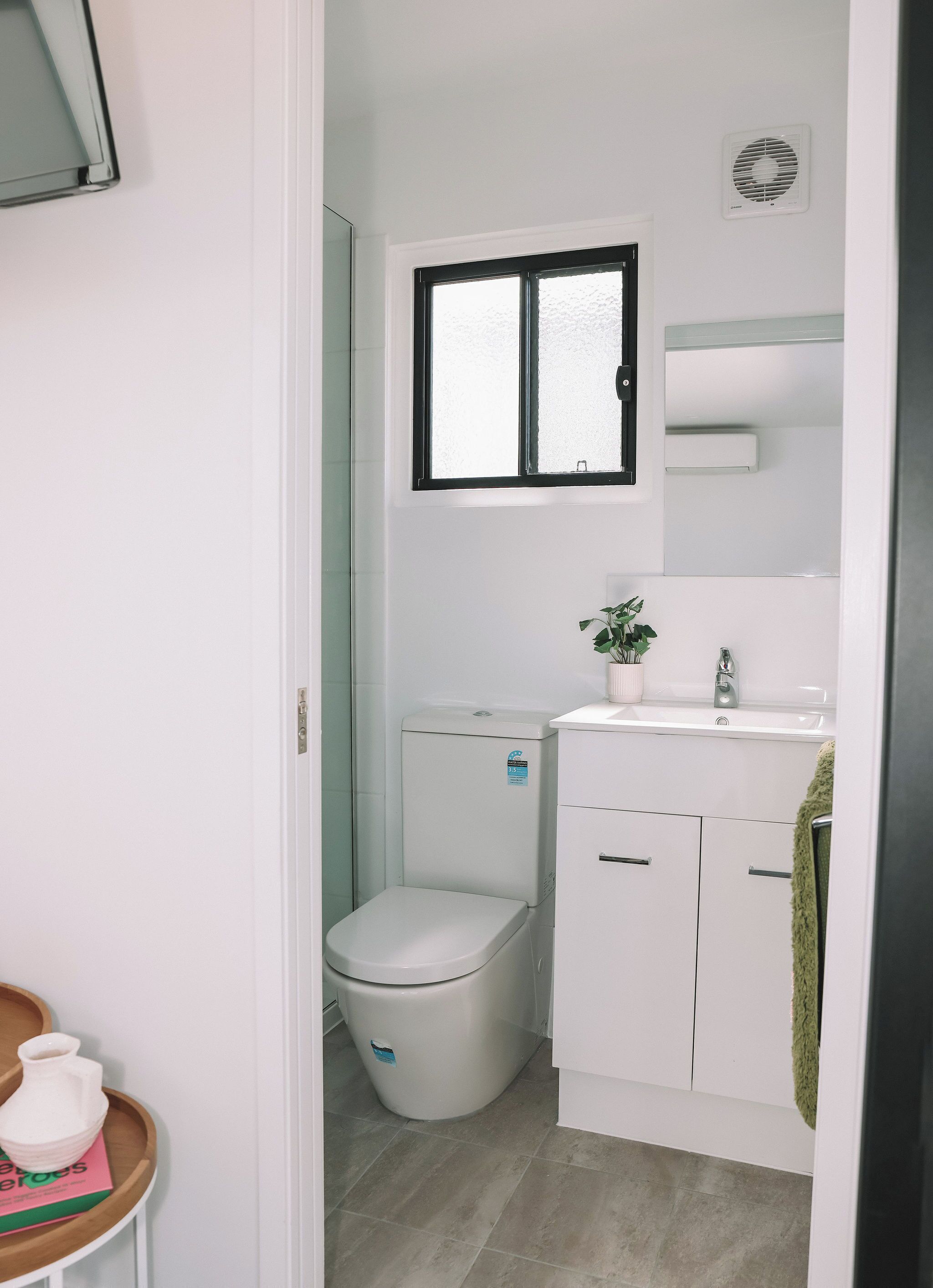A compact bathroom with a toilet, sink, and window.