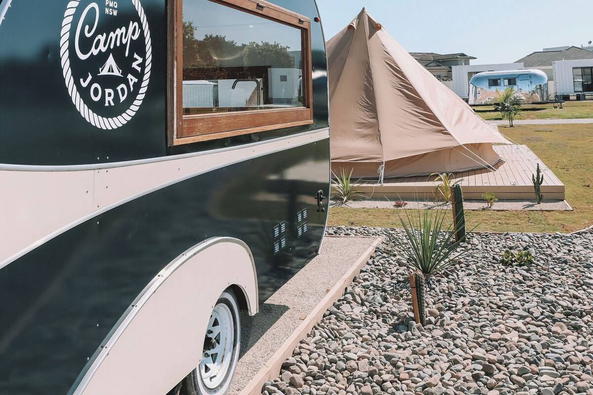 Una caravana blanco y negro con una ventana y un logotipo que dice "Camp Jordans".