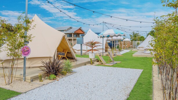 Un camping con varias tiendas de campaña, una zona de césped y un sendero de grava.