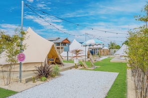 A campsite with multiple tents, a grassy area, and a gravel path. - Camp Jordans (Port Macquarie)