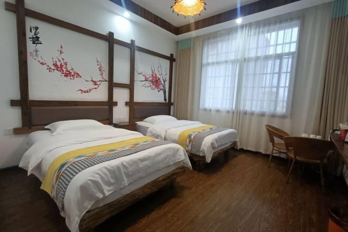 A room with two beds, a wooden floor, a desk, and a chair.