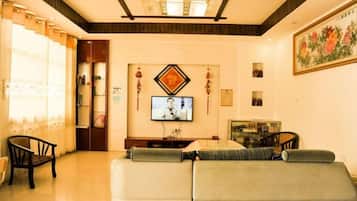 Una sala de estar con un sofá, televisor y adornos.