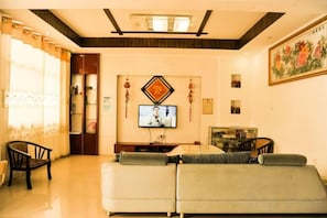 Sala de estar com sofá, televisão e objetos decorativos.