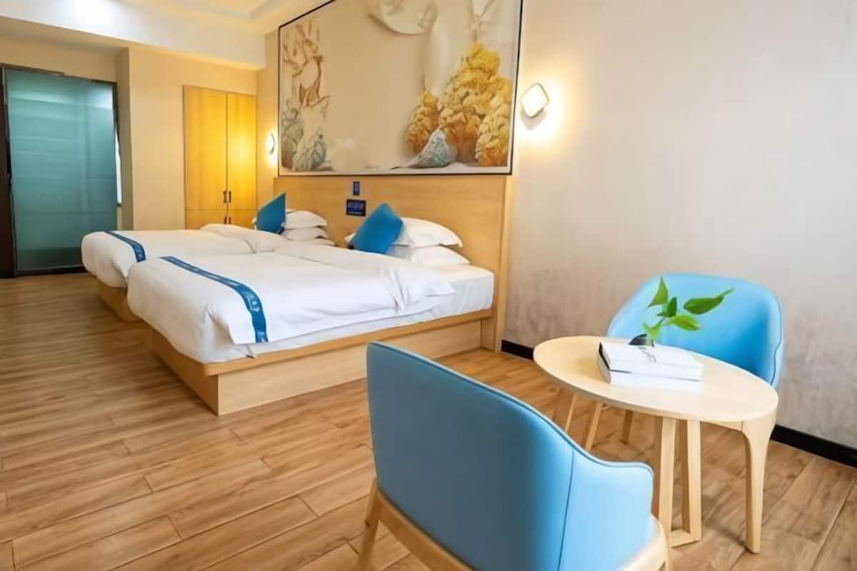 Una habitación de hotel con cama, escritorio, silla y un cuadro colgado en la pared.