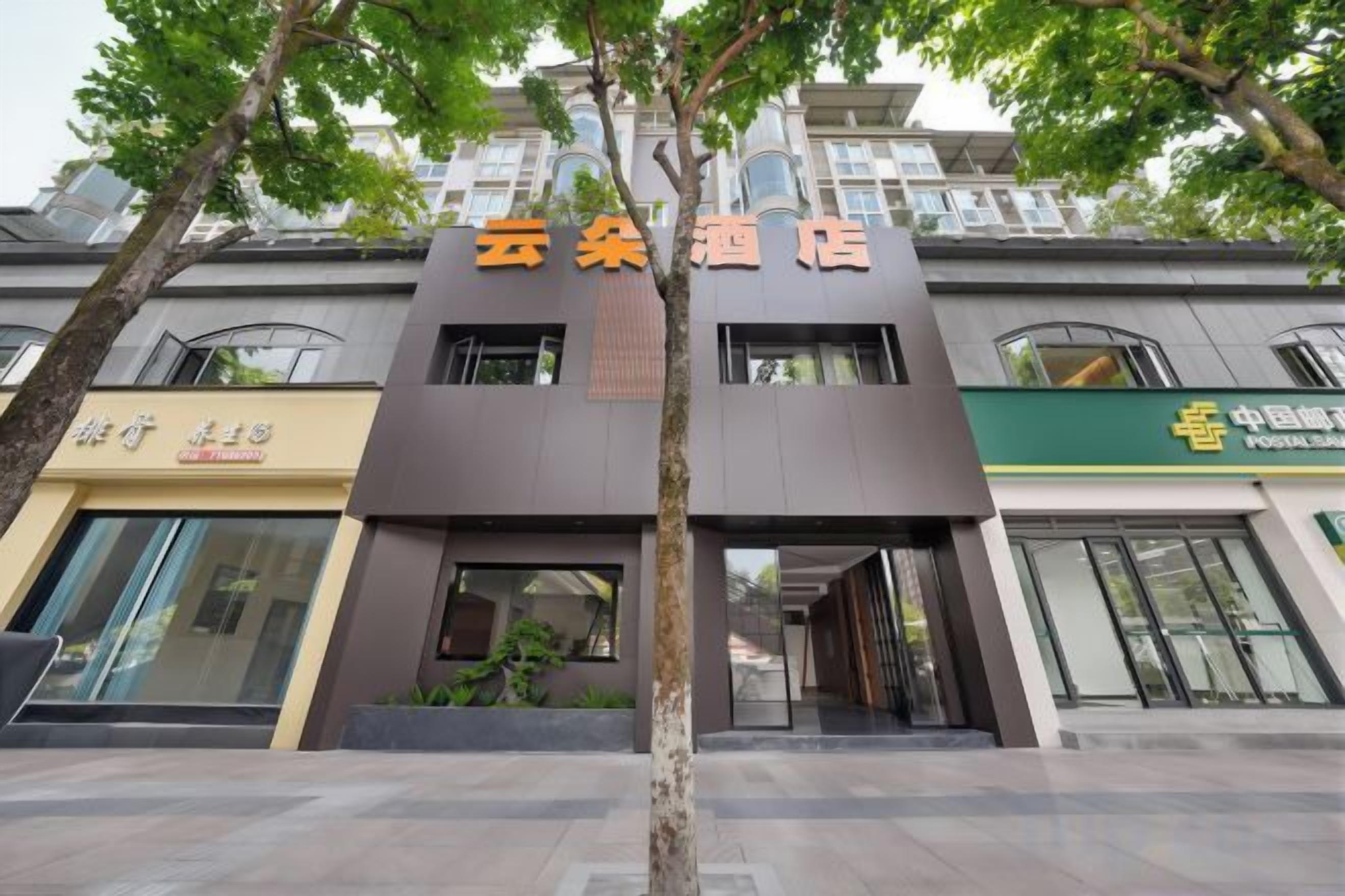 A hotel entrance with a modern facade, a visible entrance, and a signboard above the door.